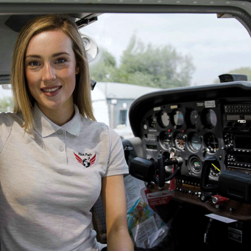 A happy young female trainee pilot inside the cockpit of a plane