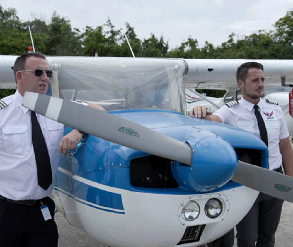 Two men standing beside a blue and white plane